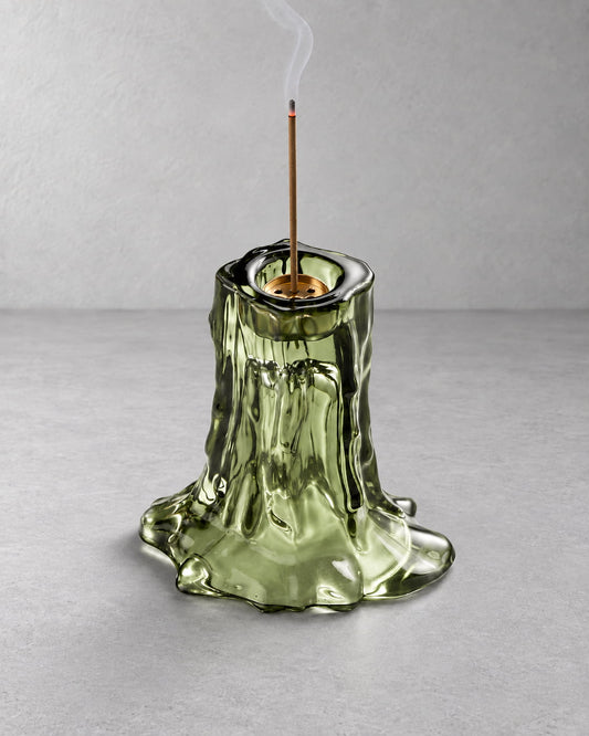 Green glass incense holder in use with a lit incense stick and soft rising smoke