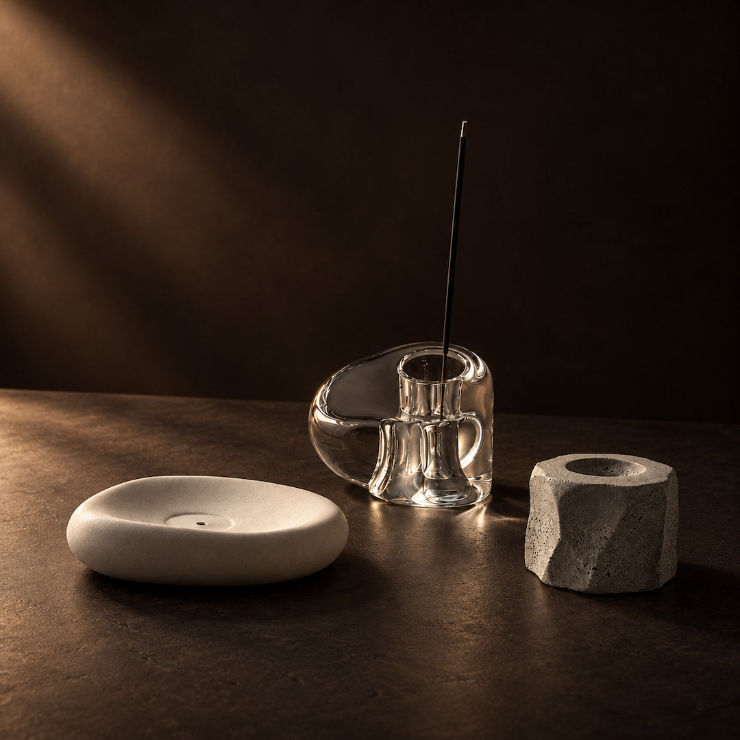 Agarwood pieces beside a burning incense stick with delicate smoke rising in a dark atmospheric setting.