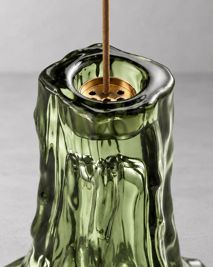 Close-up of a moss green glass incense holder showing the metal insert and molten glass texture