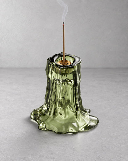Green glass incense holder in use with a lit incense stick and soft rising smoke