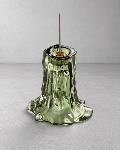 Moss green melted glass incense holder with a single incense stick on a light gray background