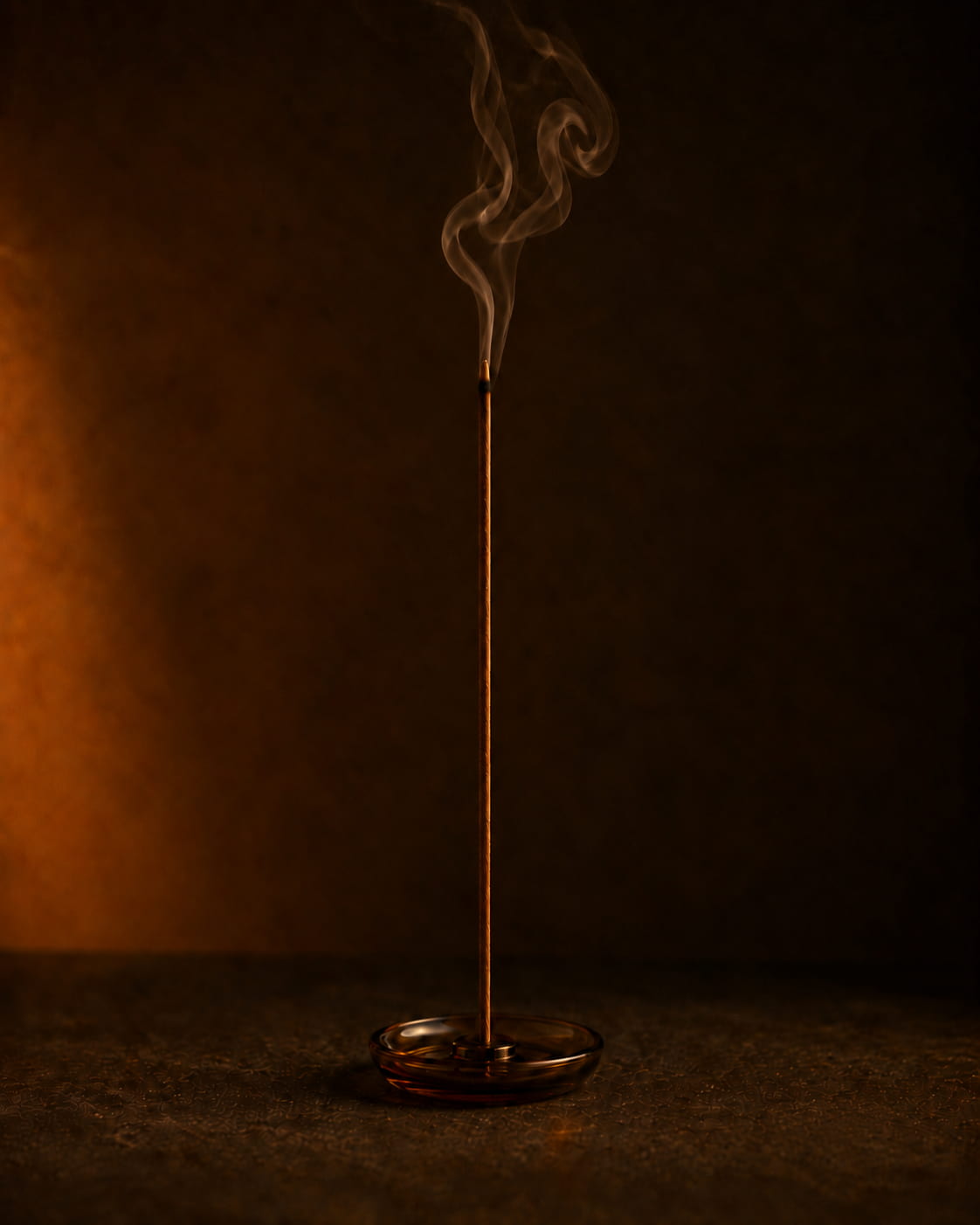 Burning agarwood incense stick releasing soft smoke after the flame is extinguished