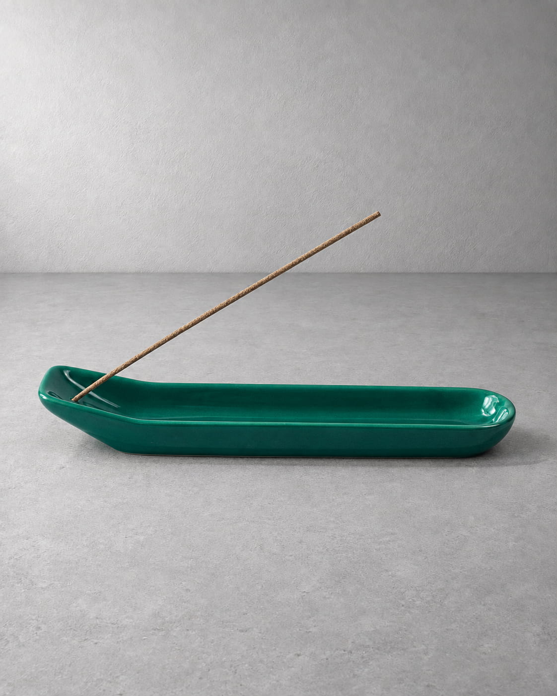 Emerald green glazed ceramic incense holder with an unlit incense stick and elongated ash-catching tray.