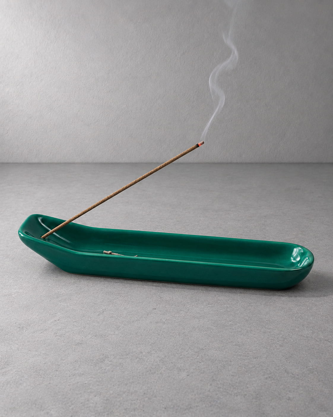 Green ceramic incense holder for sticks with burning incense, long ash-catching tray, and soft rising smoke.